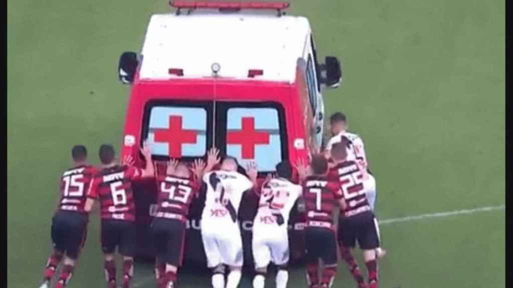 Jugadores del Vasco da Gama y del Flamengo empujan una ambulancia. Twitter: @minutouno