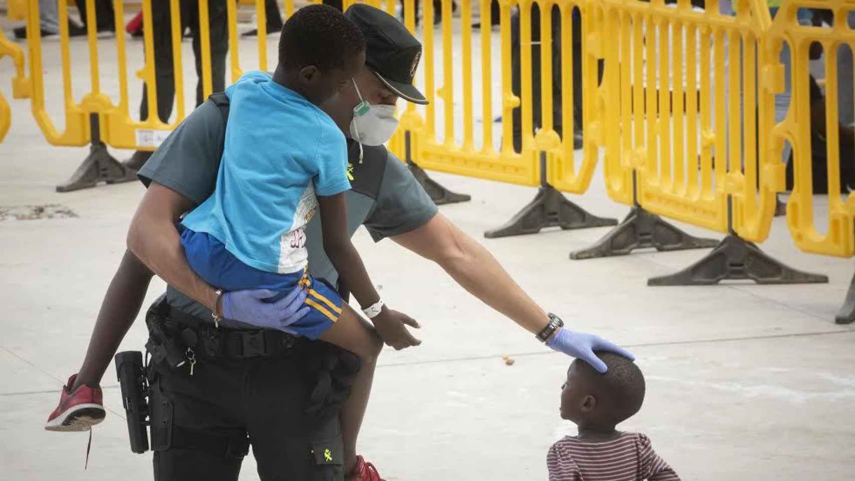 Un guardia civil atiende a dos menores inmigrantes en un polideportivo de Los Barrios (Cádiz) este verano.
