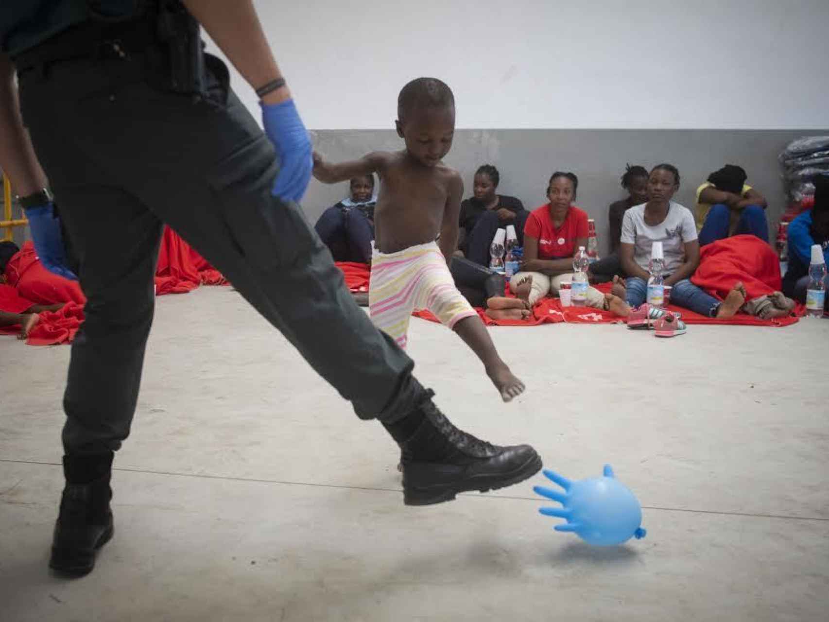 Un agente de la Guardia Civil juguetea con un niño de origen subsahariano con un globo hinchado en el puerto de Barbate (Cádiz). La imagen fue tomada durante la última crisis migratoria sufrida por España este verano.