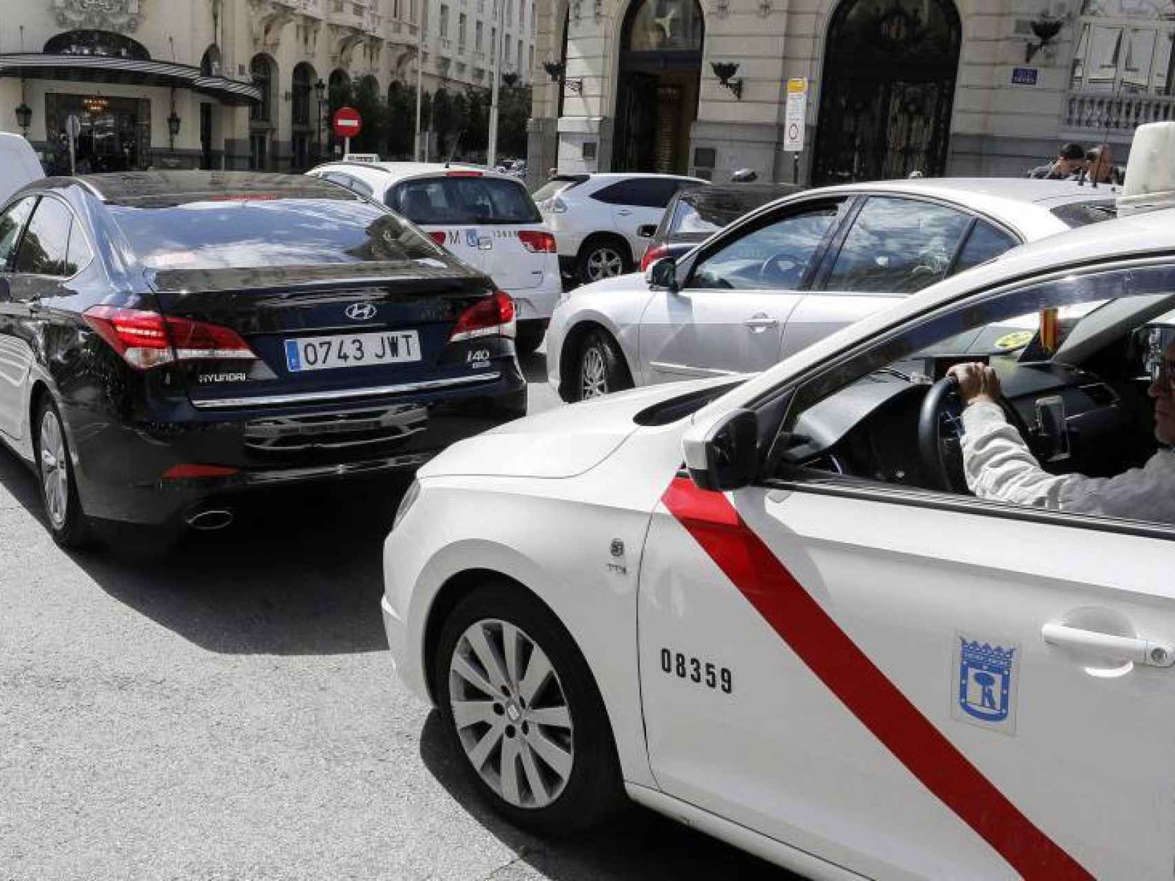 Un taxi de Madrid detrás de un vehículo VTC en las calles de Madrid.
