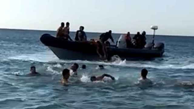 Grupo de inmigrantes marroquíes nadan para subir a bordo de una lancha como las que tradicionalmente usan los narcotraficantes para transportar hachís desde Marruecos hasta España.