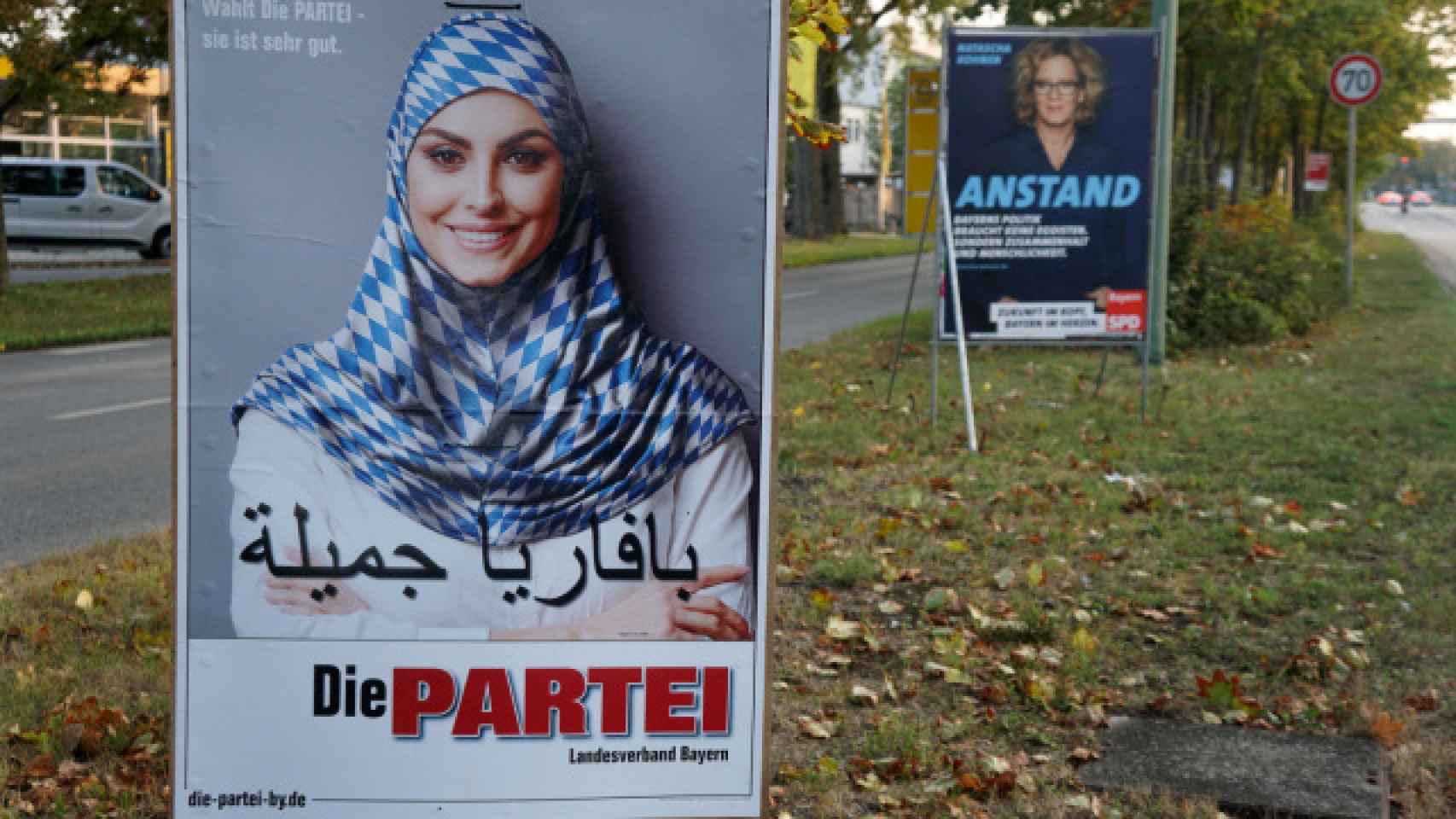 Un cartel con una mujer musulmana y la bandera de Baviera como chador.