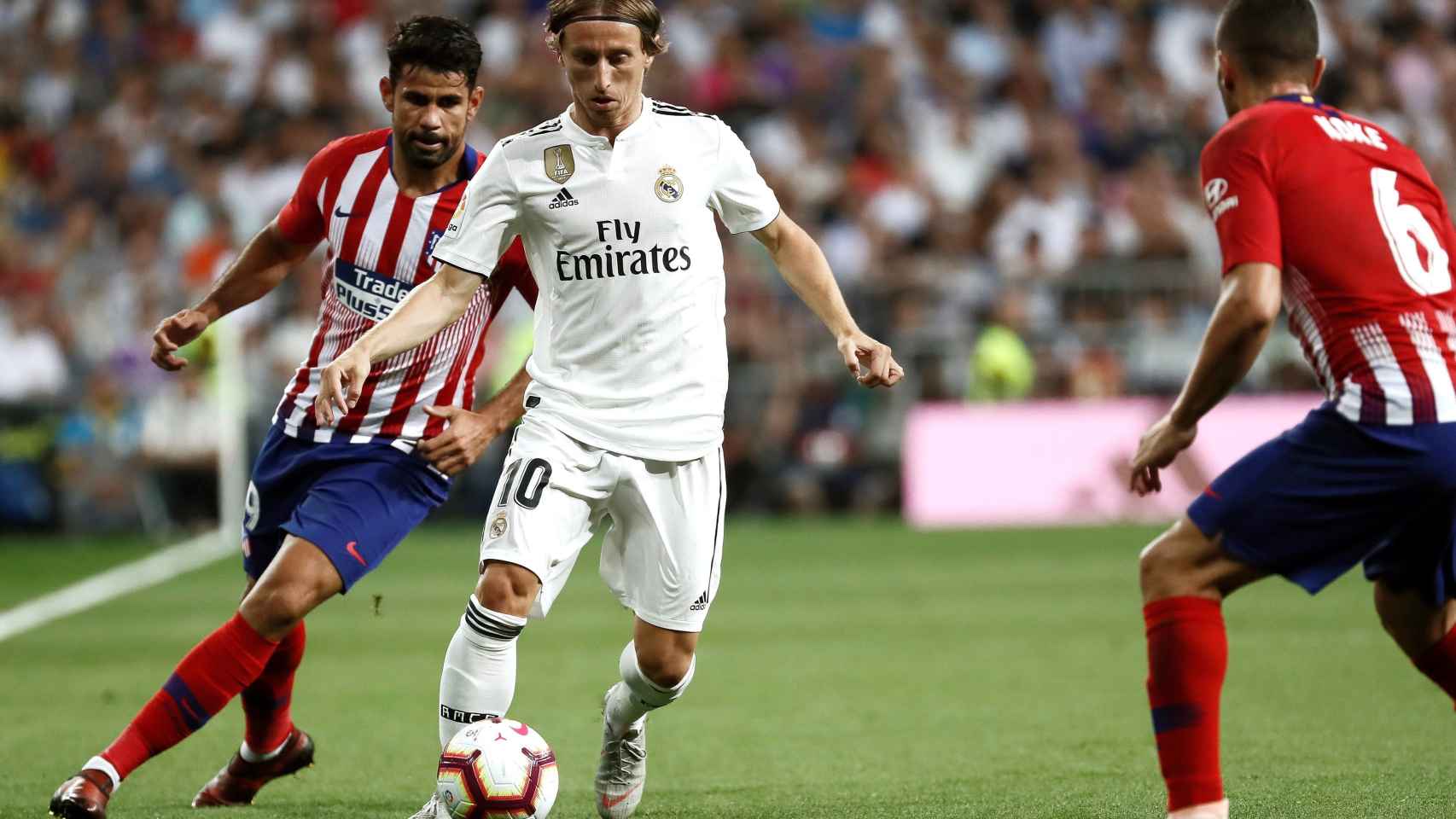 El centrocampista croata del Real Madrid, Luka Modric, conduce el balón ante el delantero hispano-brasileño del Atlético de Madrid, Diego Costa