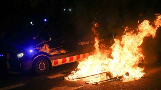Momento en el que un coche de los Mossos pasaba anoche junto a una barricada situada frente al Parlament.