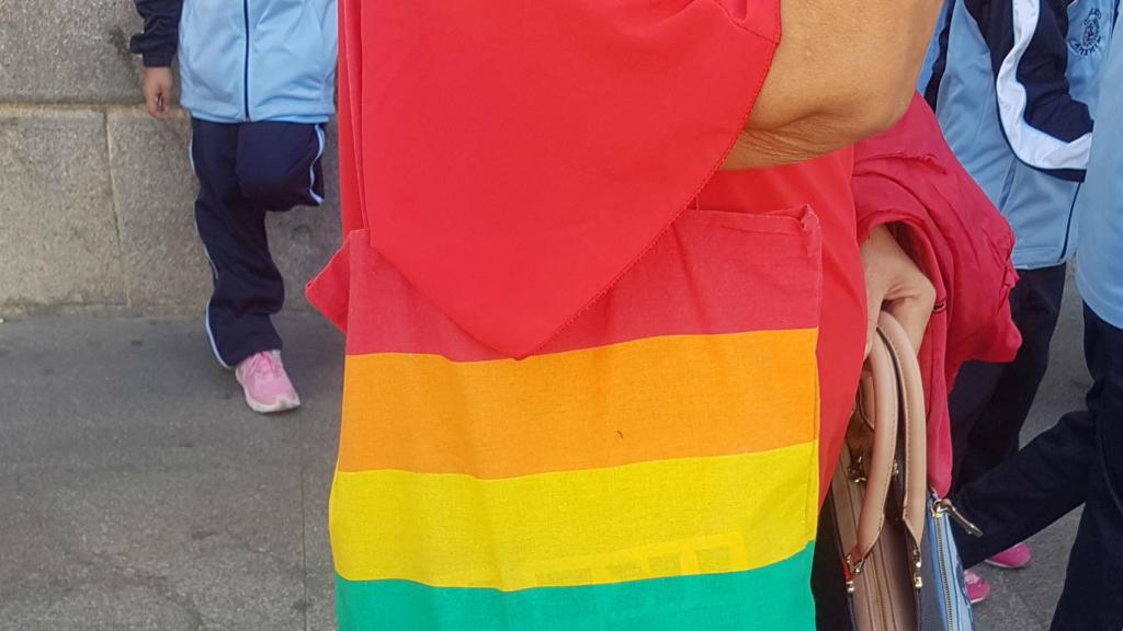 Una señora vestida con bolso de la bandera del Orgullo Gay.