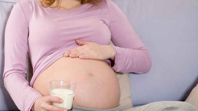 Una mujer embarazada toma un vaso de leche.