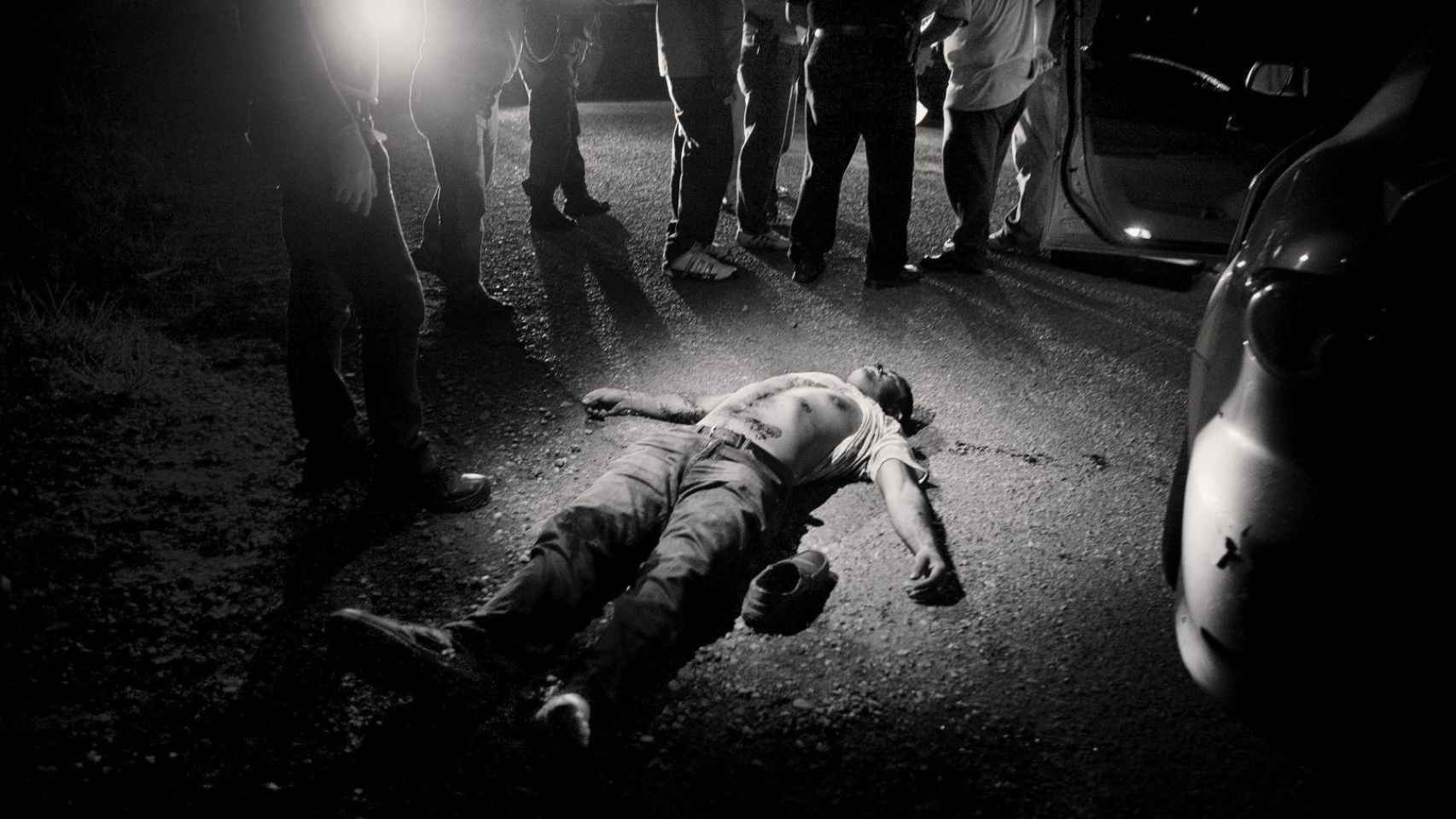 Varias personas observan un cadáver que yace descamisado en el suelo. Foto: Javier Arcenillas / Word Press Photo