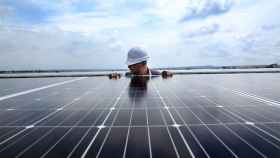 Un trabajador instala una placa en un parque fotovoltaico.