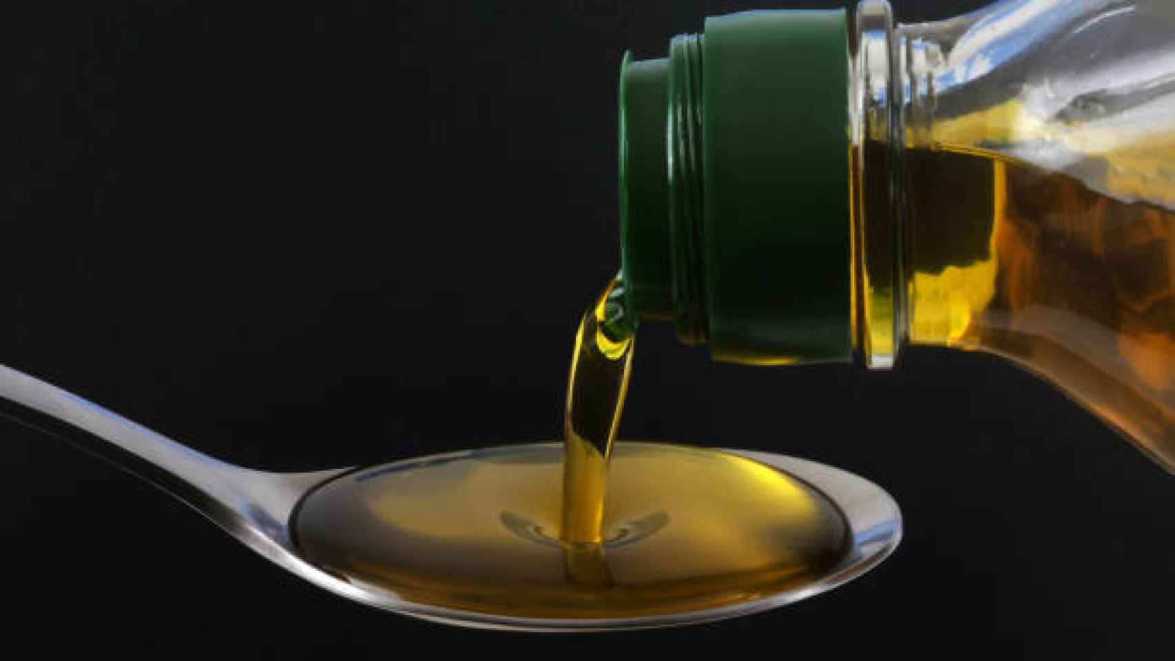 Un chorro de aceite de oliva se escurre a través de una cuchara.