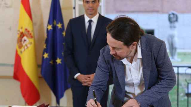 Pablo Iglesias firma el acuerdo con Pedro Sánchez en la Moncloa.