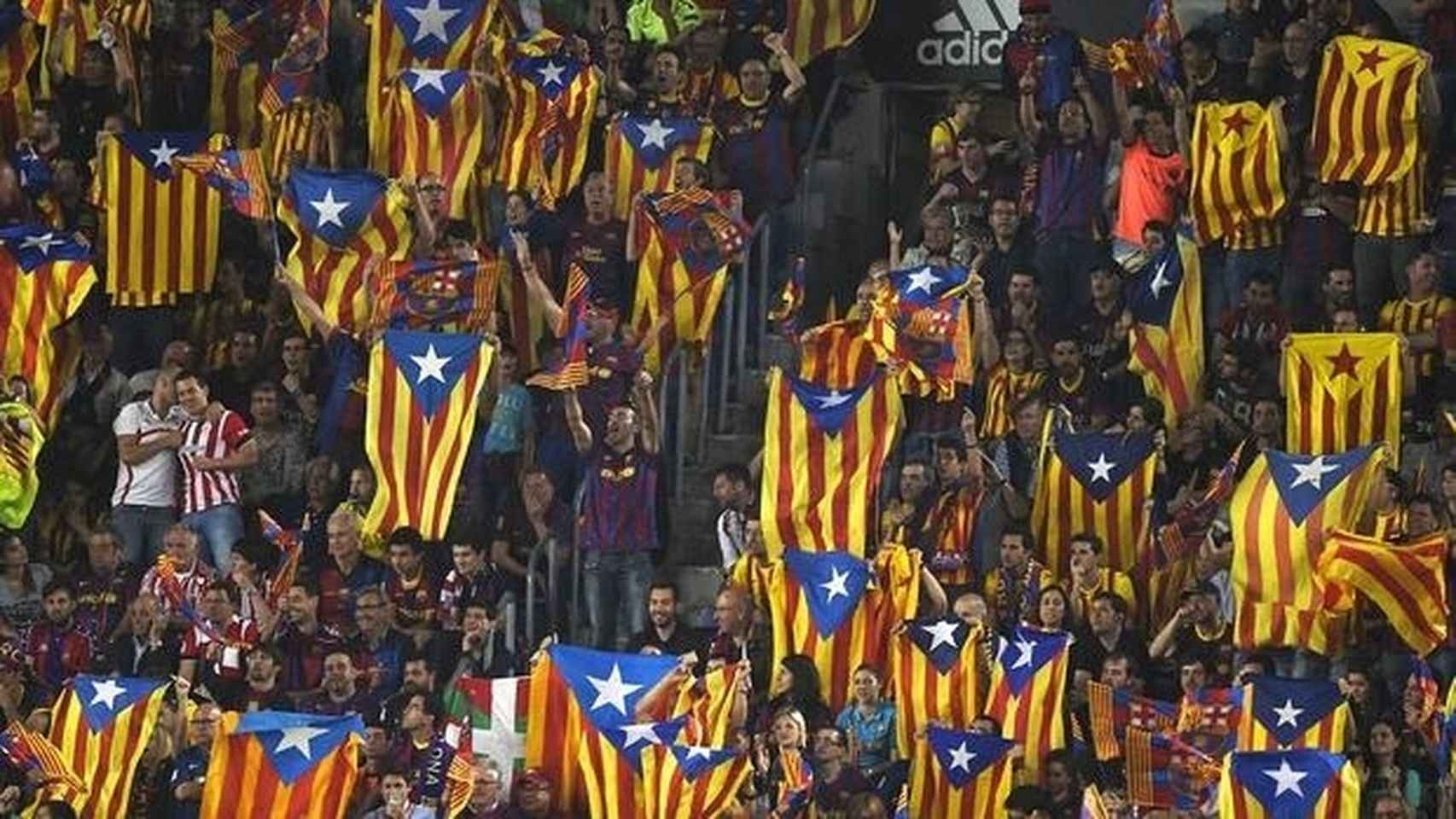 Aficionados del Barcelona sujetando esteladas