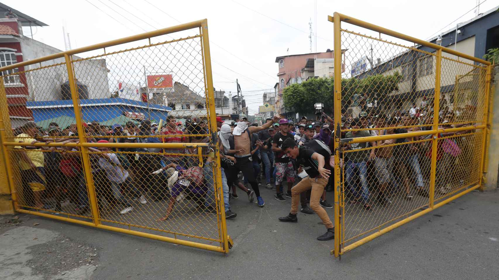 Migrantes hondureños rompen la valla fronteriza entre Guatemala y México.