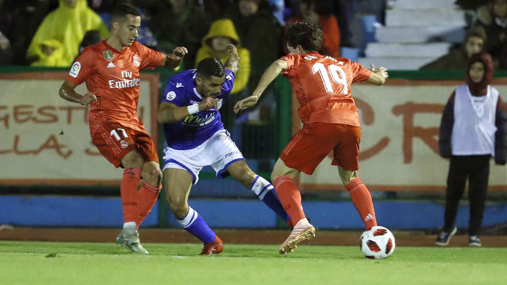 El centrocampista del Melilla Juan Ramón Ruano ante Lucas Vázquez y Álvaro Odiozoloa