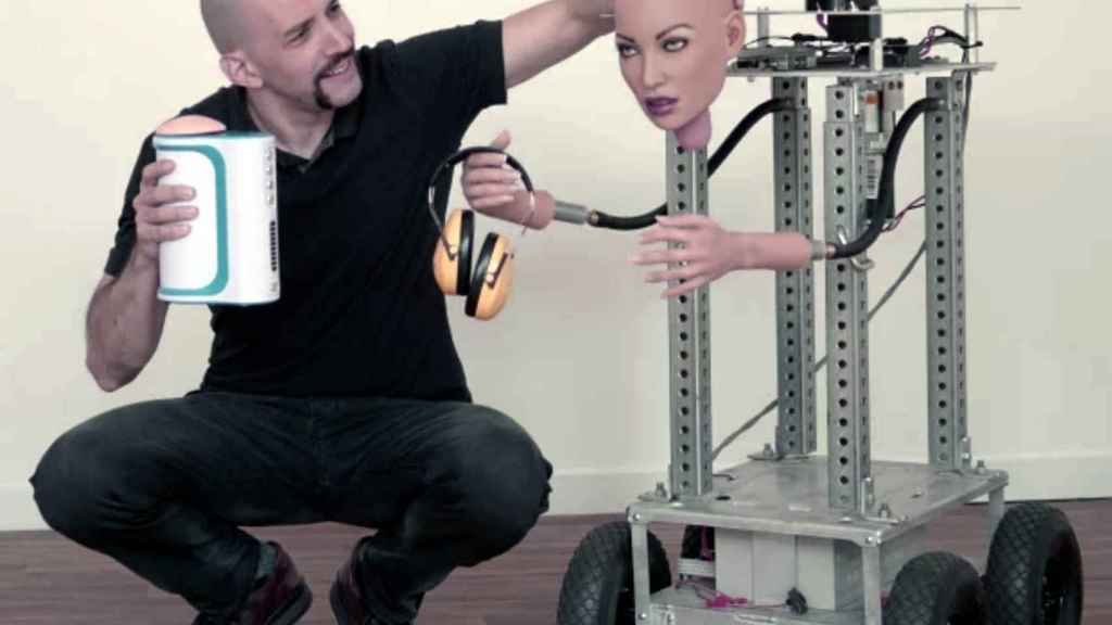 Brian Sloan con las manos ocupadas: el 'Autoblow' en la mano derecha y el robot prototipo en la izquierda.