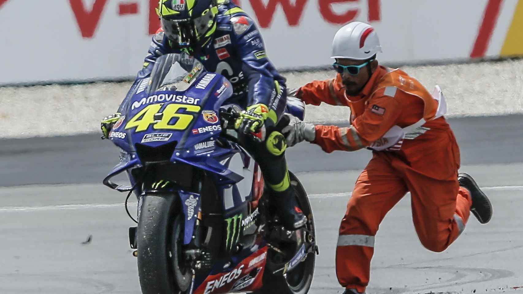 Un comisario de pista ayuda a Rossi a volver a la carrera, tras la caída en la curva 1 de Sepang.