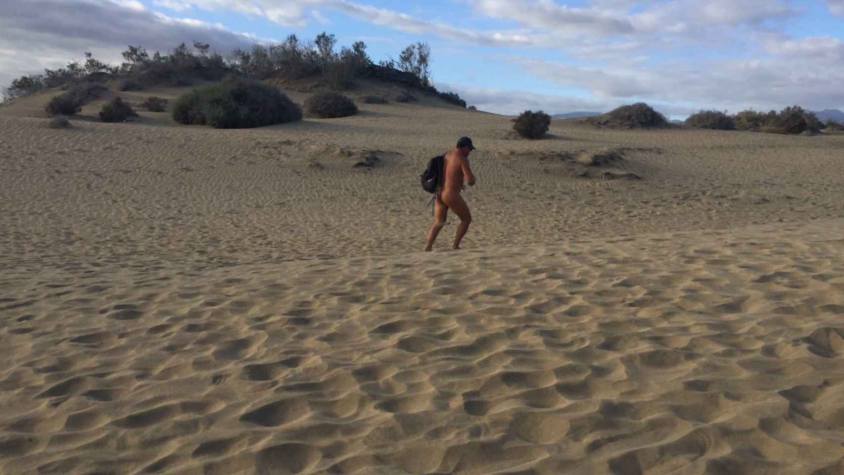 Un nudista solitario pasea entre las dunas buscando a alguien que esté teniendo sexo