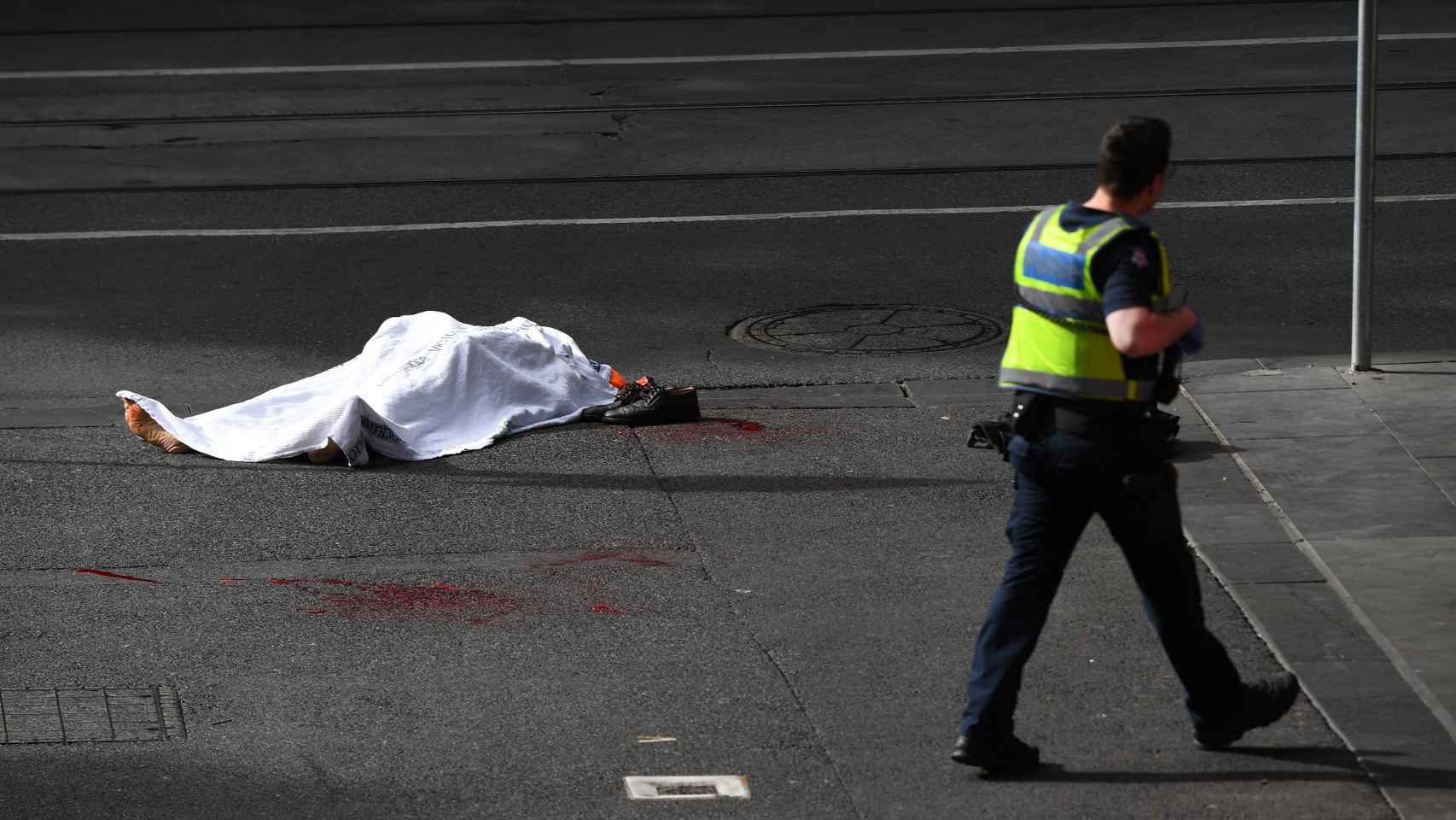 El cadáver de una víctima yace sobre el asfalto tras el ataque.