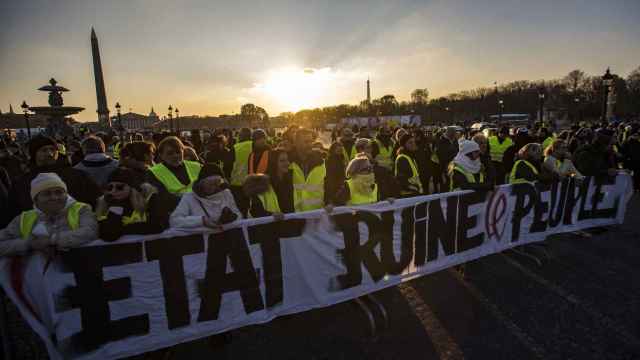 Manifestación de chalecos amarillos en la plaza de la Concordia de París con una pancarta que acusa al Estado de ser la ruina del pueblo.