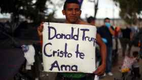 Un migrante muestra una pancarta con el lema 'Donald Trump, Cristo te ama', en Tijuana.