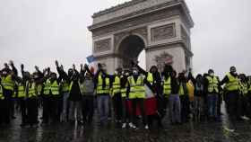 Los 'chalecos amarillos' forman ante la policía en el Arco del triunfo de París.