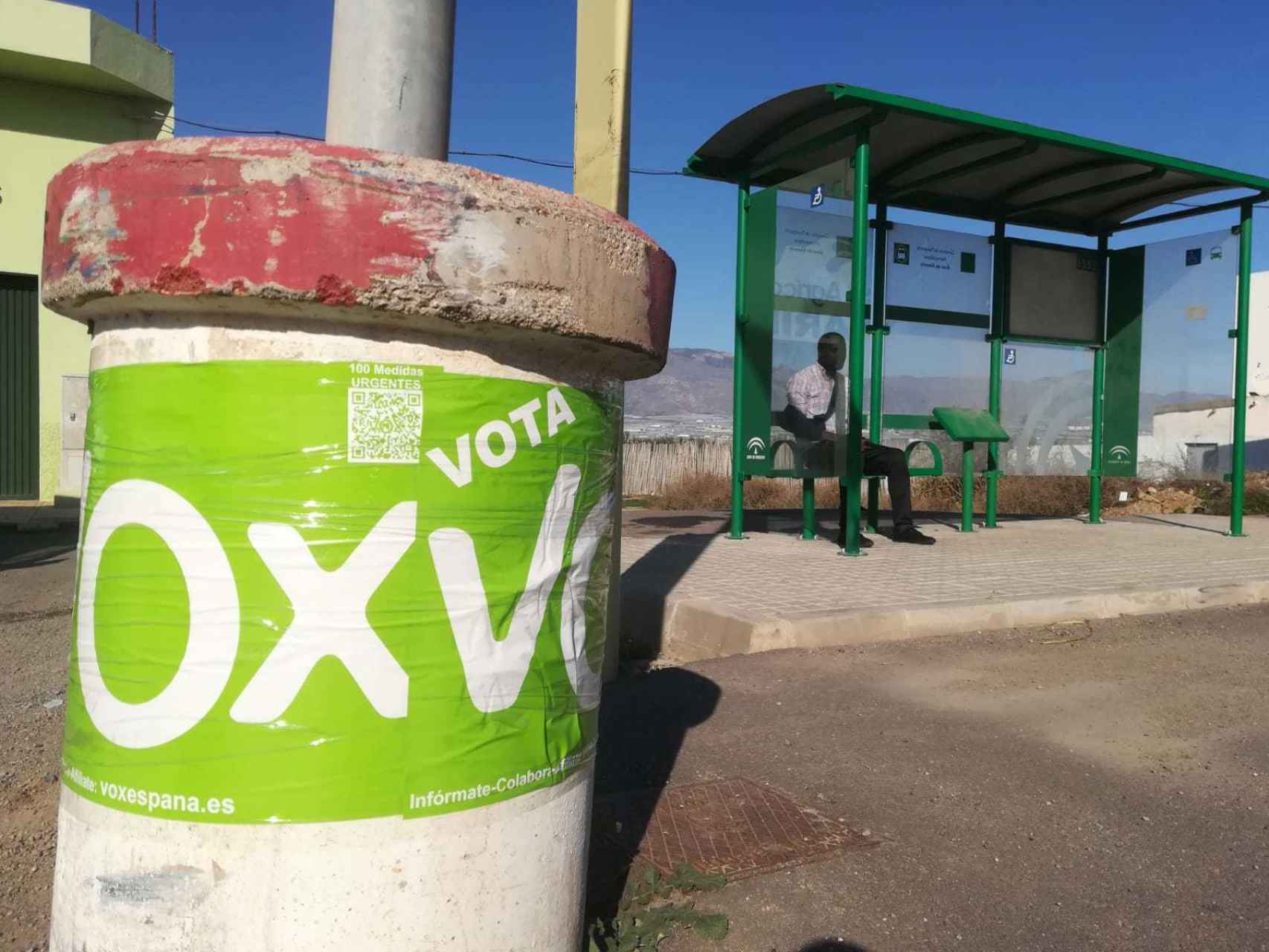 Propaganda electoral de Vox delante de una parada de autobús en la que esperaba sentado un inmigrante subsahariano.