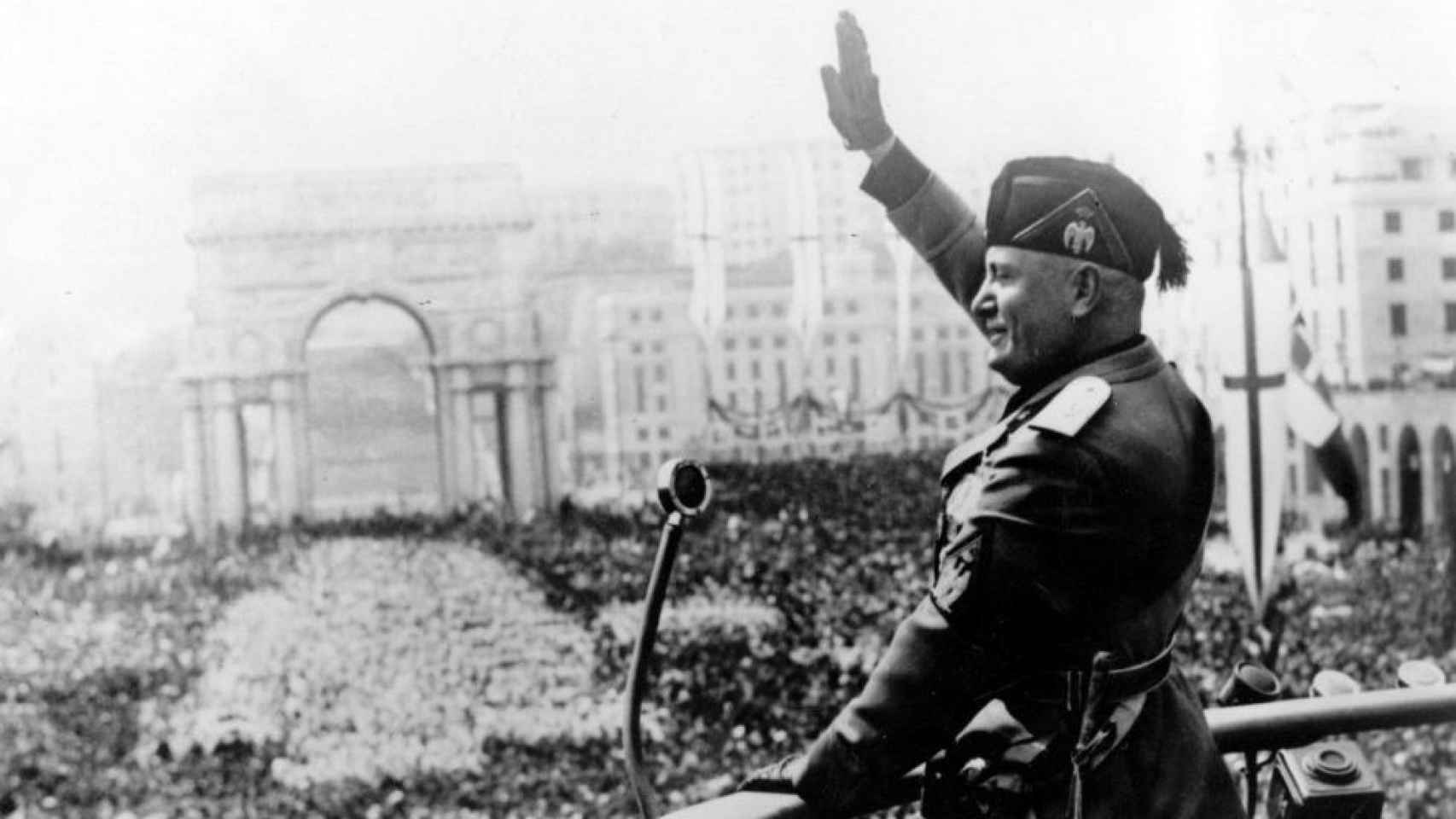Benito Mussolini haciendo el saludo fascista en un acto.