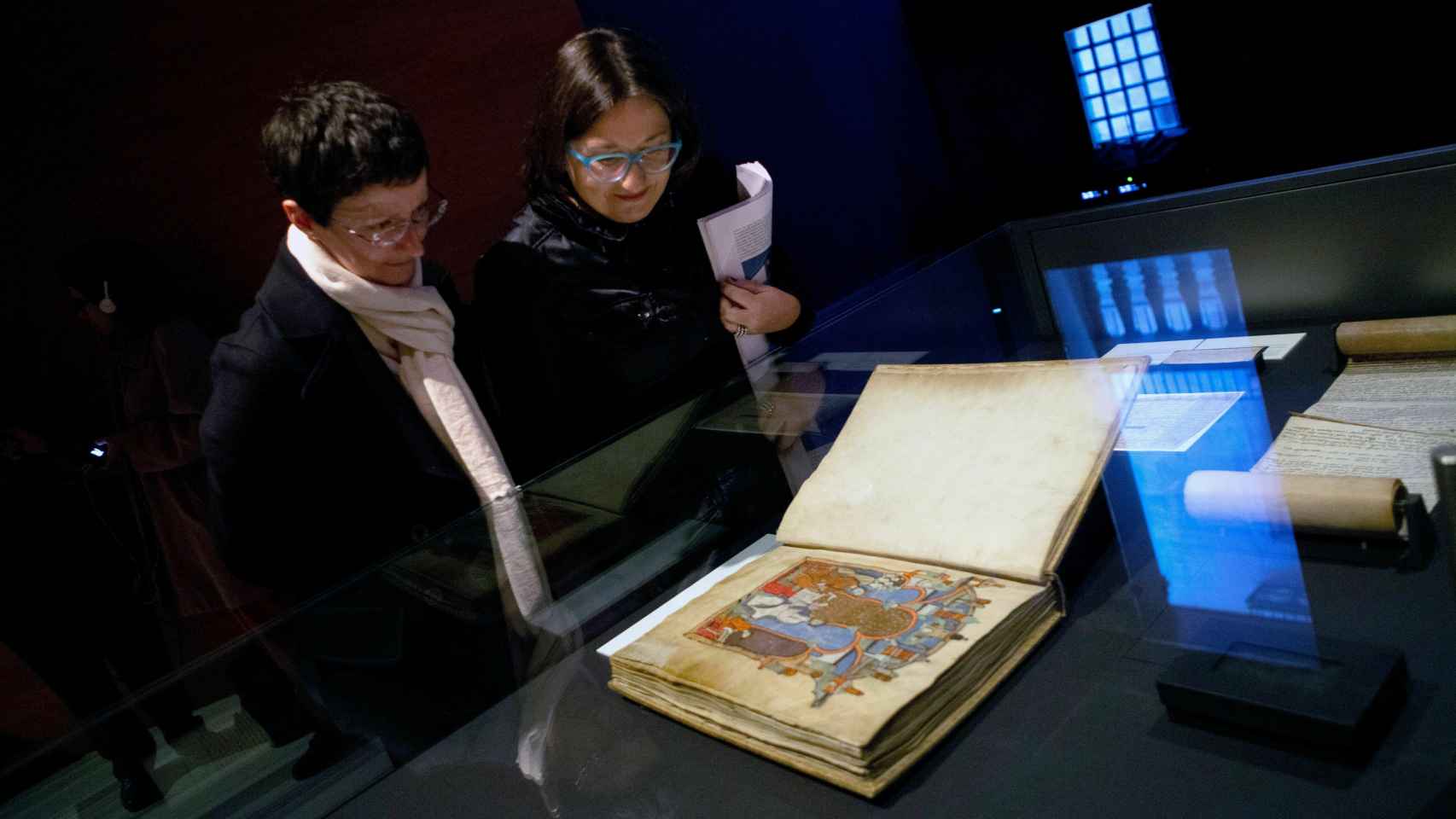 Dos visitantes observan el Gran Libro de los Feudos, un cartulario de documentos relativos a las relaciones feudales de los reyes de Aragón y condes de Barcelona en la Alta Edad Media.