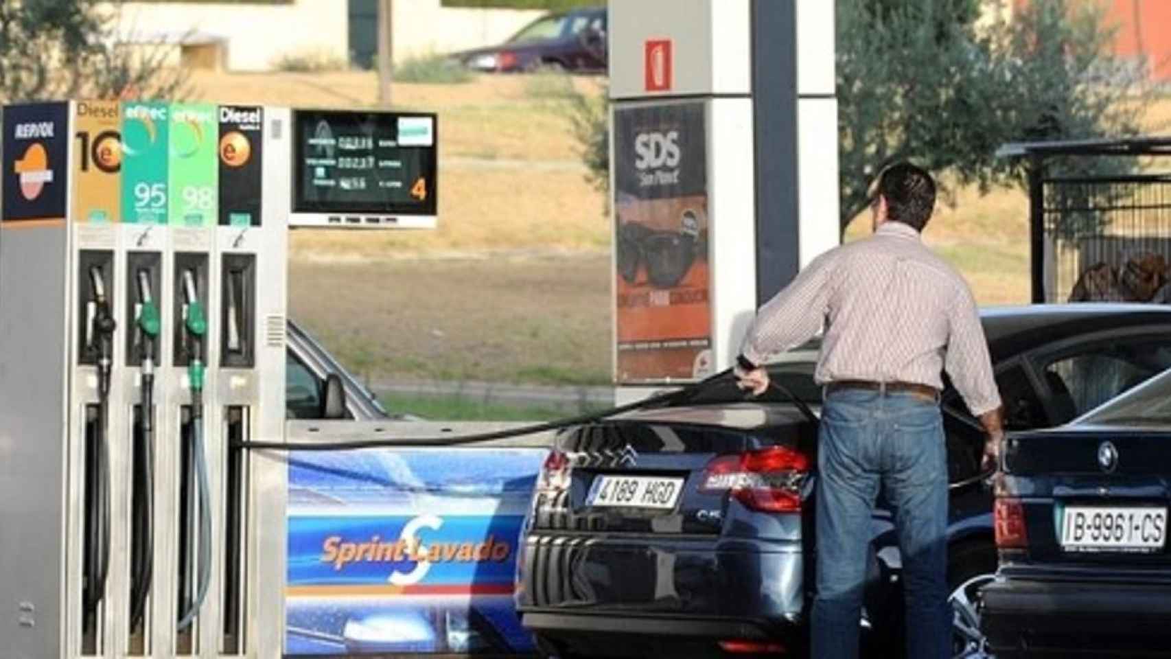 Un hombre echando gasolina a su vehículo en una estación de servicio.