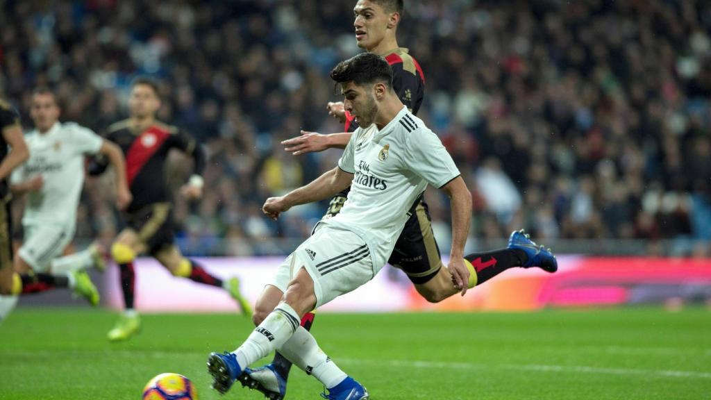 Marco Asensio pelea un balón con el defensa uruguayo del Rayo Vallecano, Emiliano Velázquez