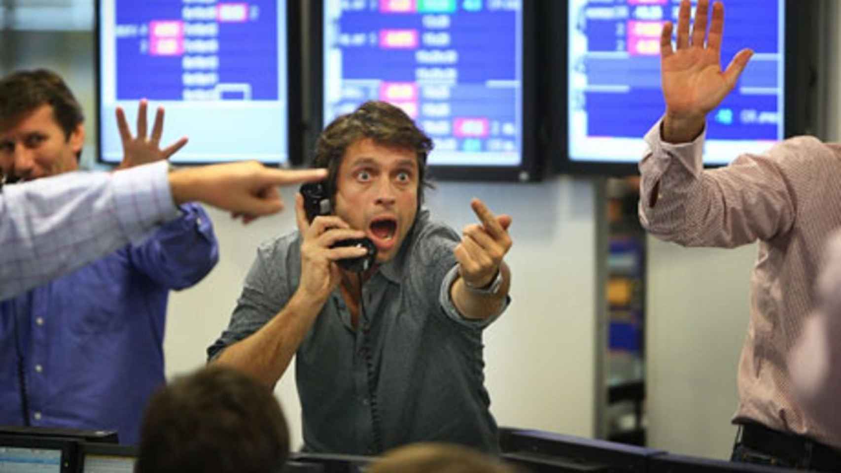 Varios brókeres con gesto de entusiamo en una sala de negociación de valores.