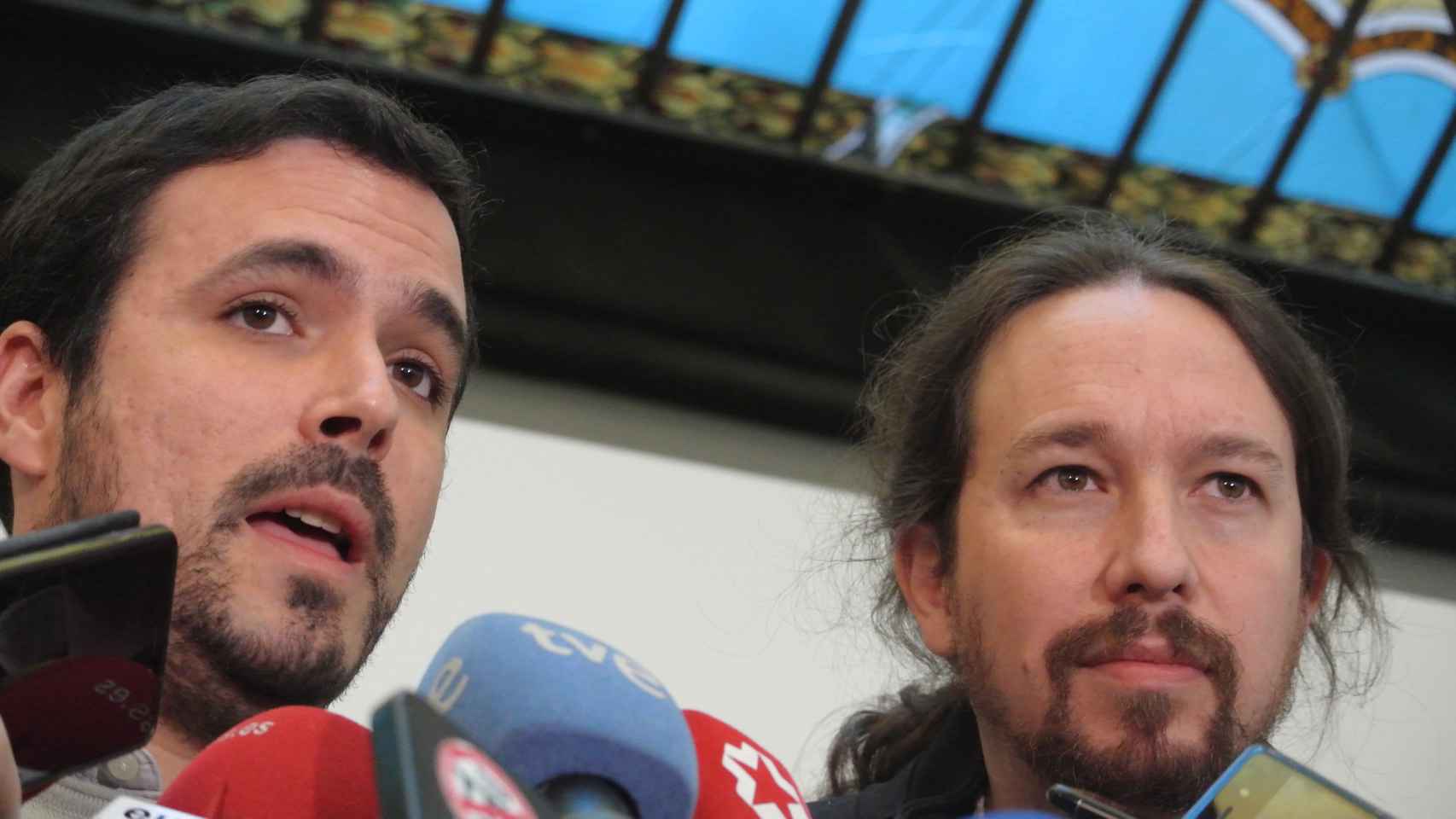 Alberto Garzón atiende a los medios ante la mirada de Pablo Iglesias.