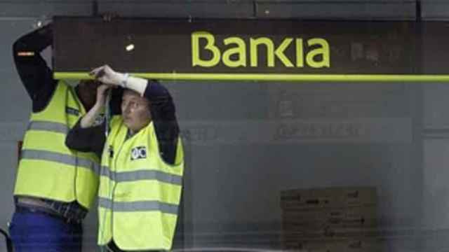 Empleados retirando un cartel de Bankia.