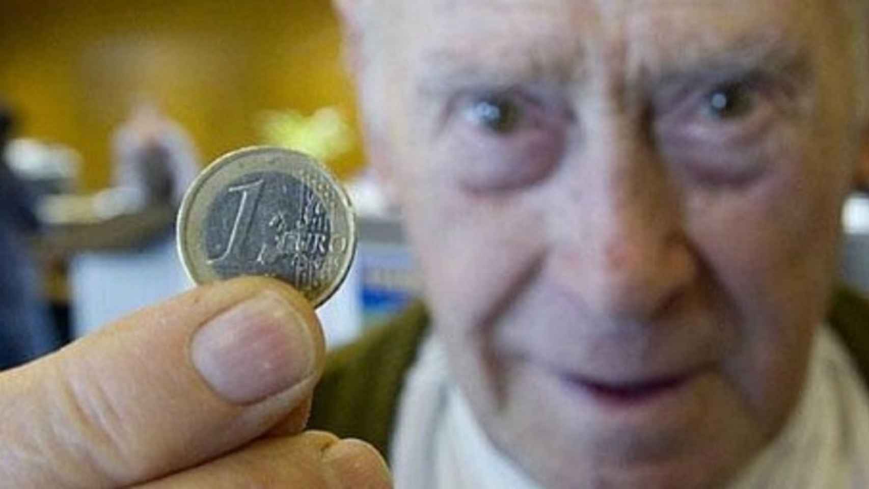 Un jubilado muestra una moneda de un euro.