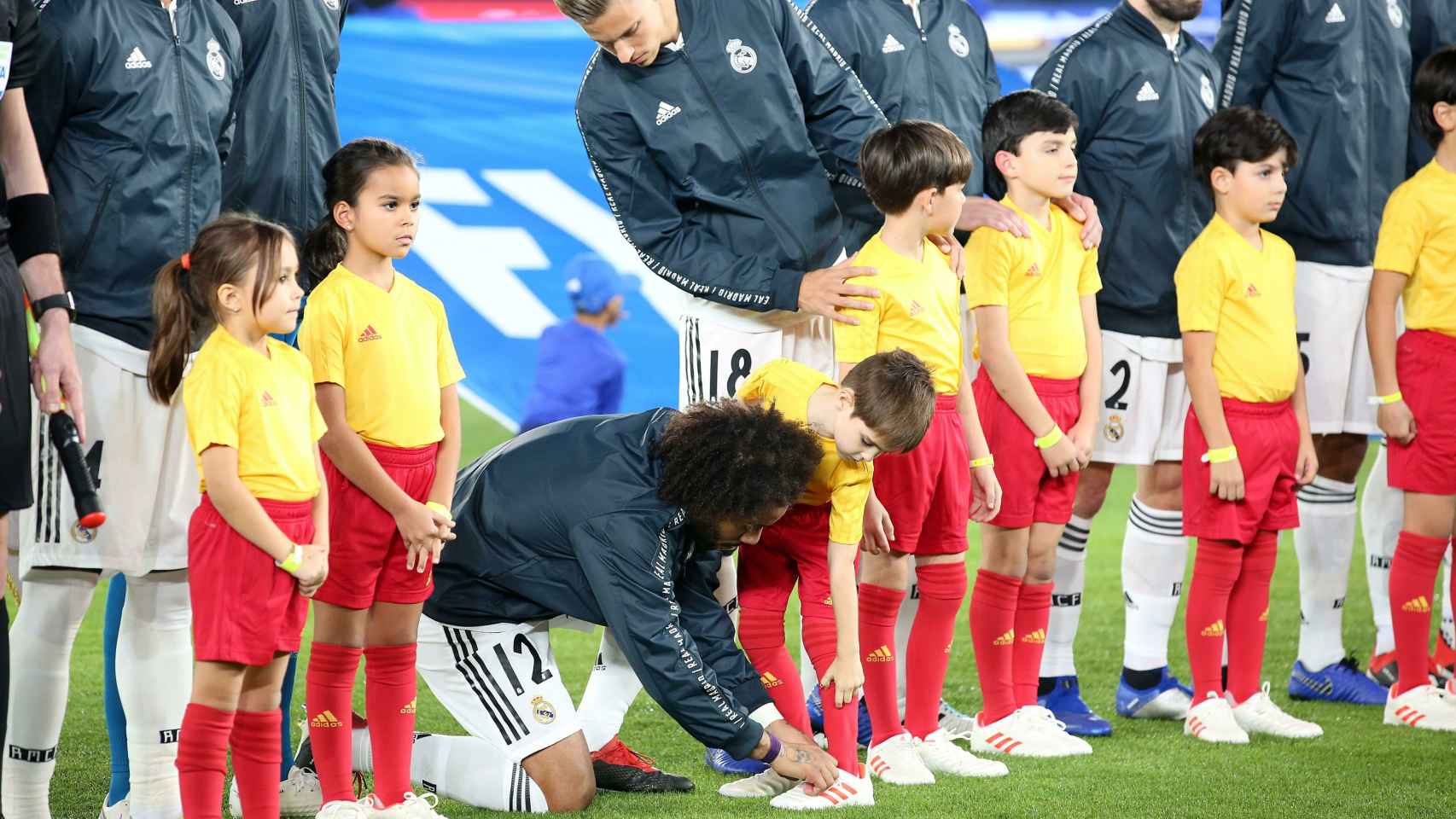 El lateral izquierdo Marcelo ata el cordón del zapato a un niño durante el posado previo a la semifinal del Mundial de Clubes