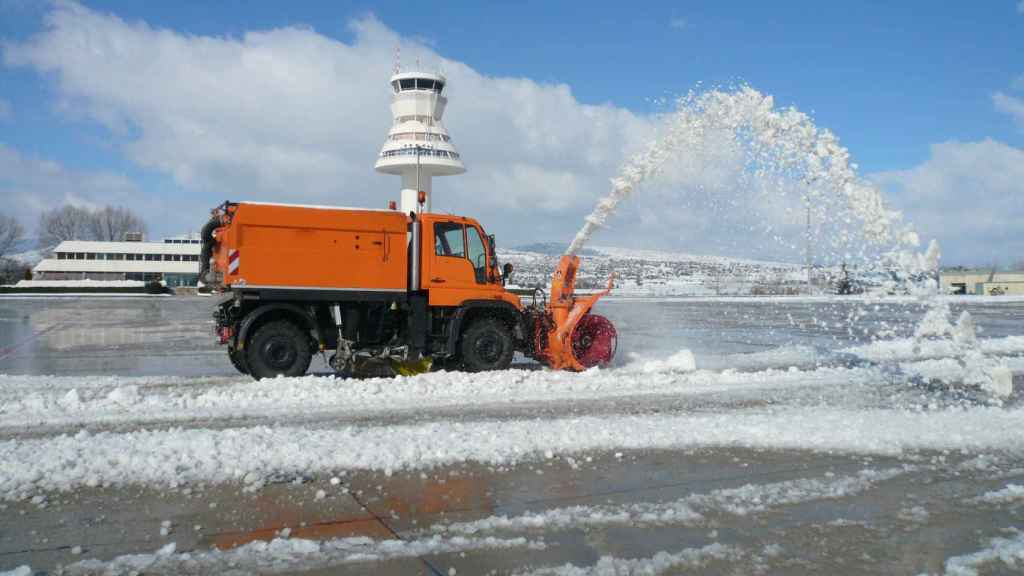 Imagen de un vehículo quitando la nieve acumulada en la pista del aeropuerto