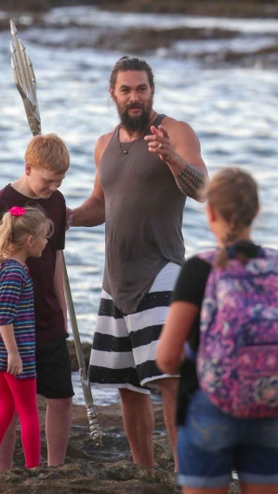 Jason Momoa jugando a Aquaman con unos chicos en la playa.