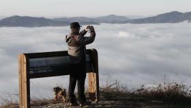 Un paseante fotografía el amanecer sobre la niebla que cubre la comarca de Pamplona.