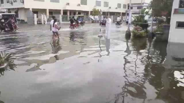 Los peatones y los vehículos se mueven a lo largo de una calle inundada en Daet.