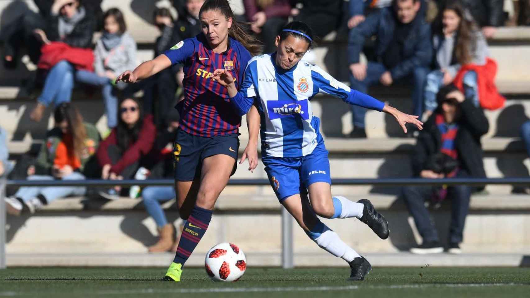 Dos jugadoras del FC Barcelona femenino y del RCD Espanyol femenino disputan un balón