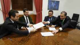 Teodoro García Egea y Javier Ortega Smith intercambian documentos para la firma ante Juanma Moreno y Francisco Serrano.