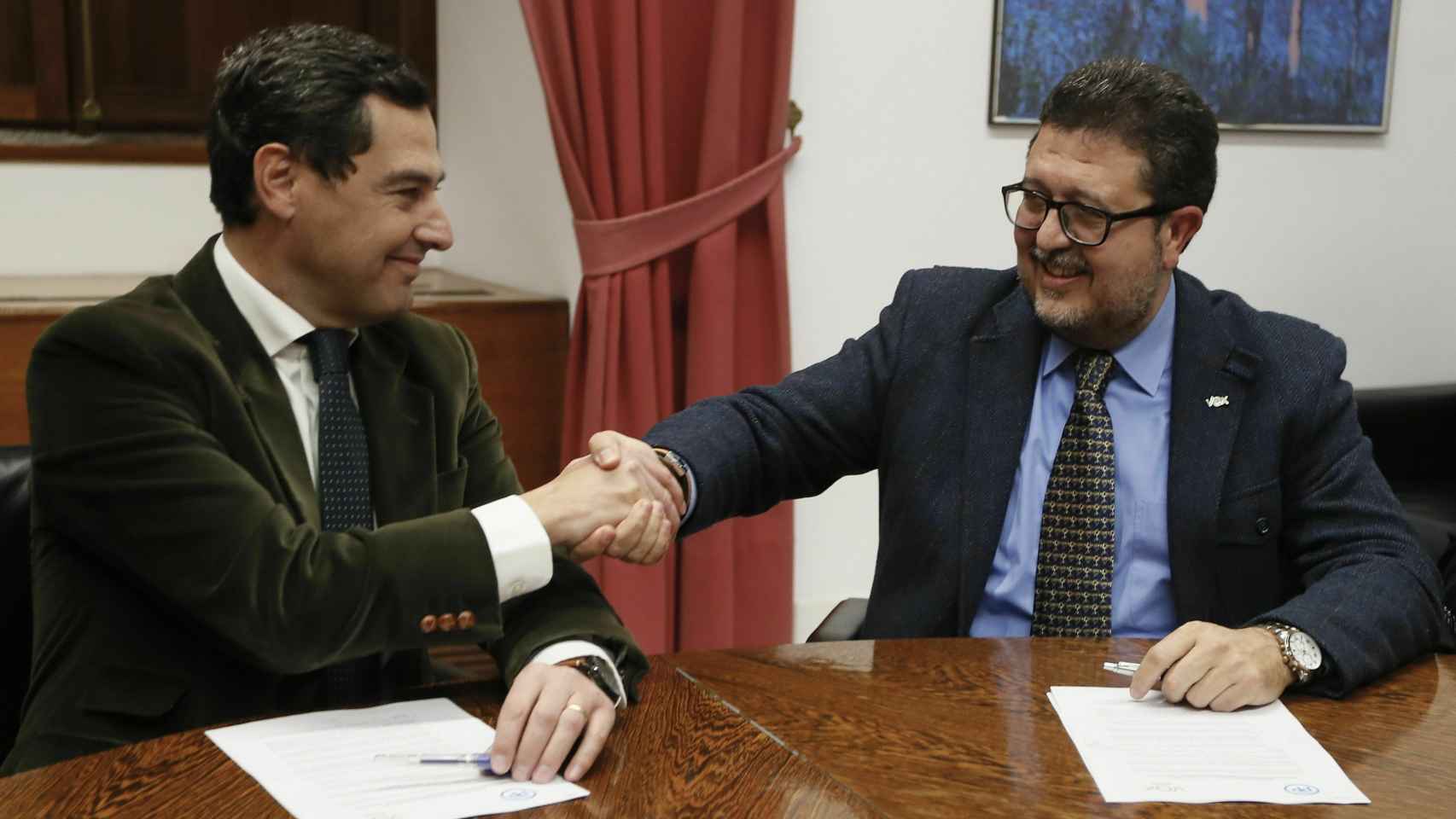El presidente del PP-A, Juanma Moreno (i), estrecha la mano con el líder andaluz de Vox, Francisco Serrano.