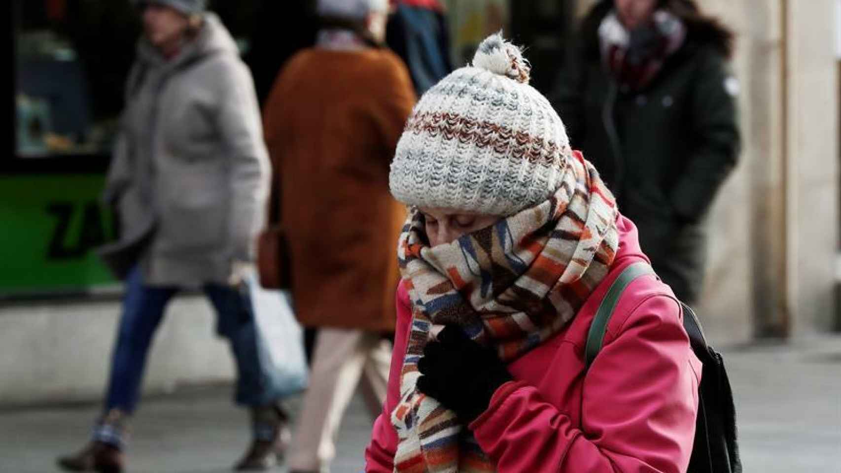 Una mujer se protege del intenso frío en Pamplona.