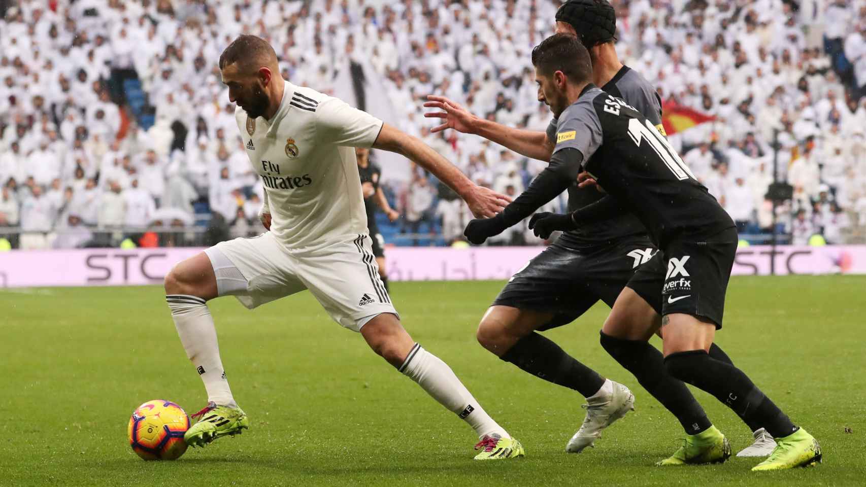 Karim Benzema, perseguido por dos jugadores del Sevilla