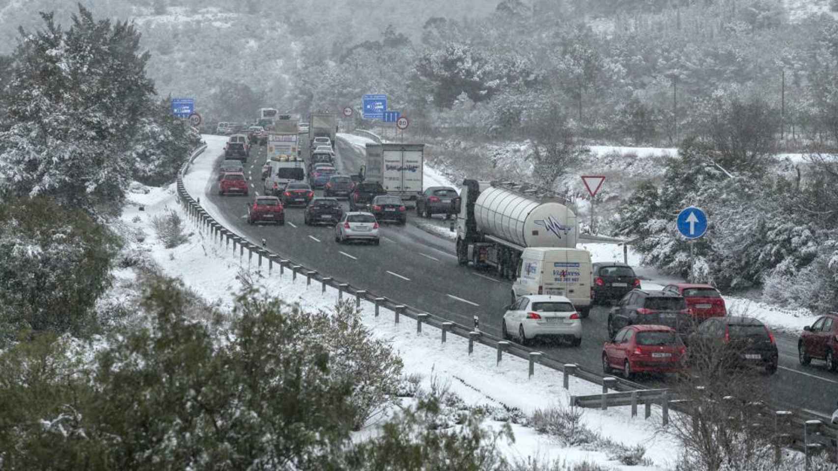 Varios vehículos detenidos en la carretera por la nieve.