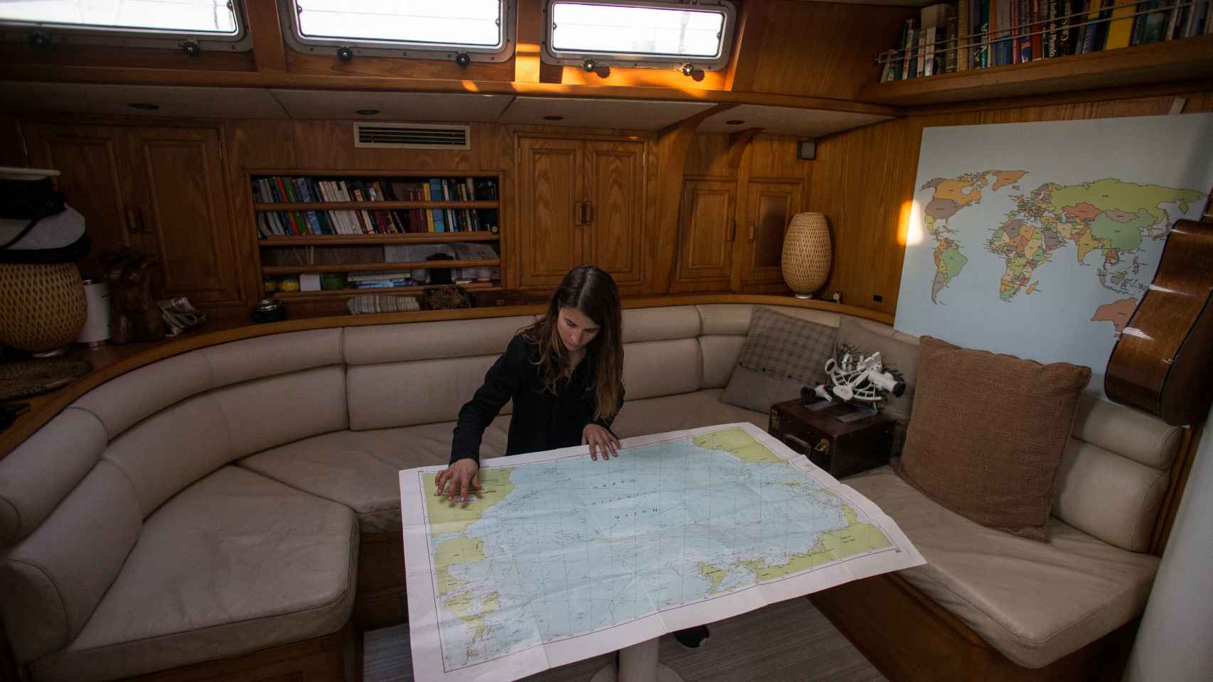 Paula consultando las cartas naúticas en el interior del velero.