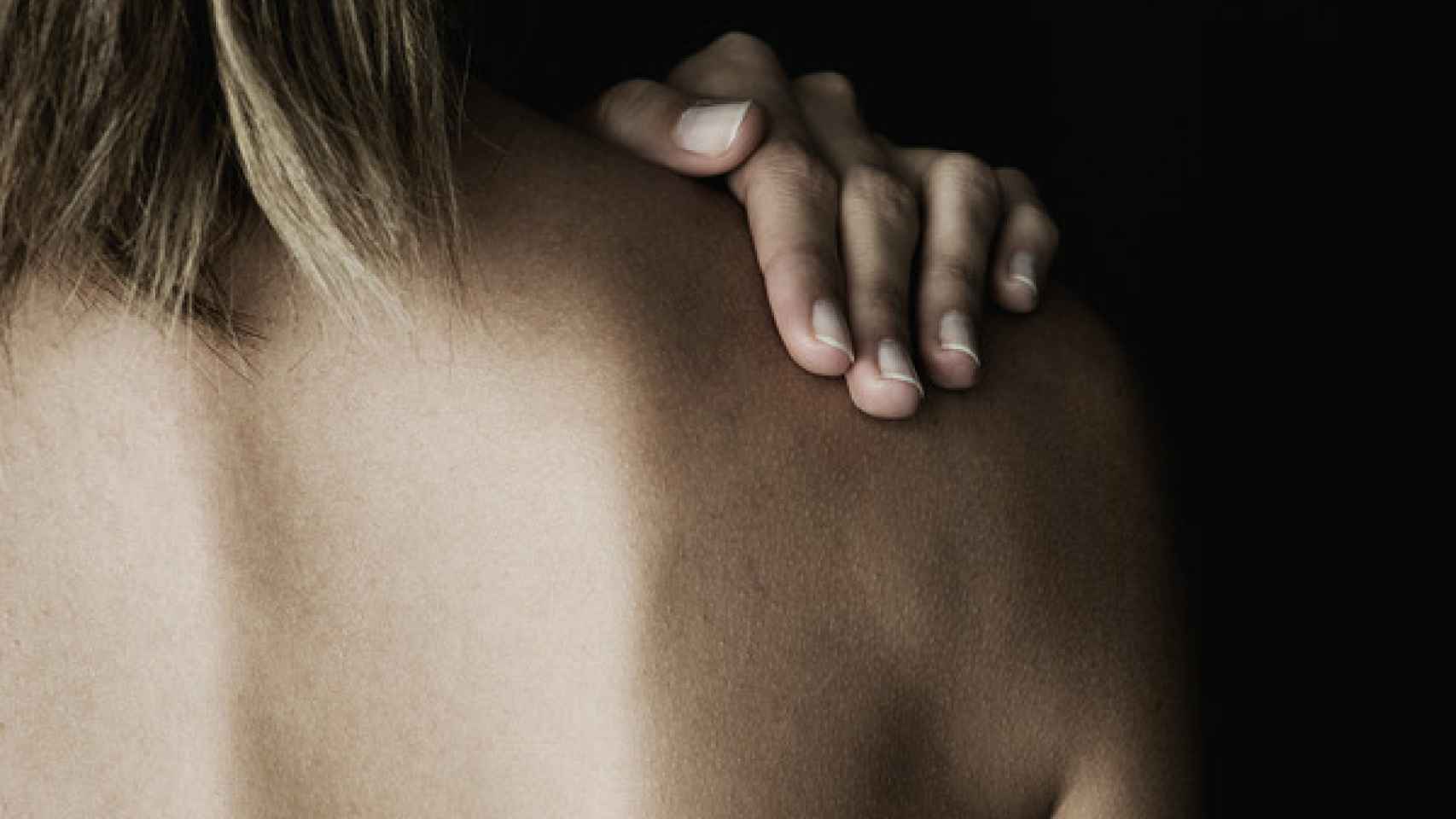 Una mujer se toca el hombro dolorido.