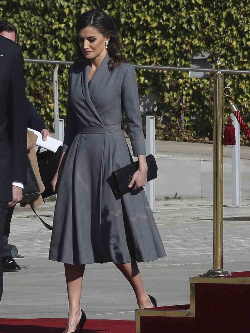 La reina Letizia con vestido gris silueta 'wrap' en el aeropuerto rumbo a Marruecos.
