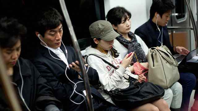 Varios pasajeros en el metro de Seúl con sus smartphones.
