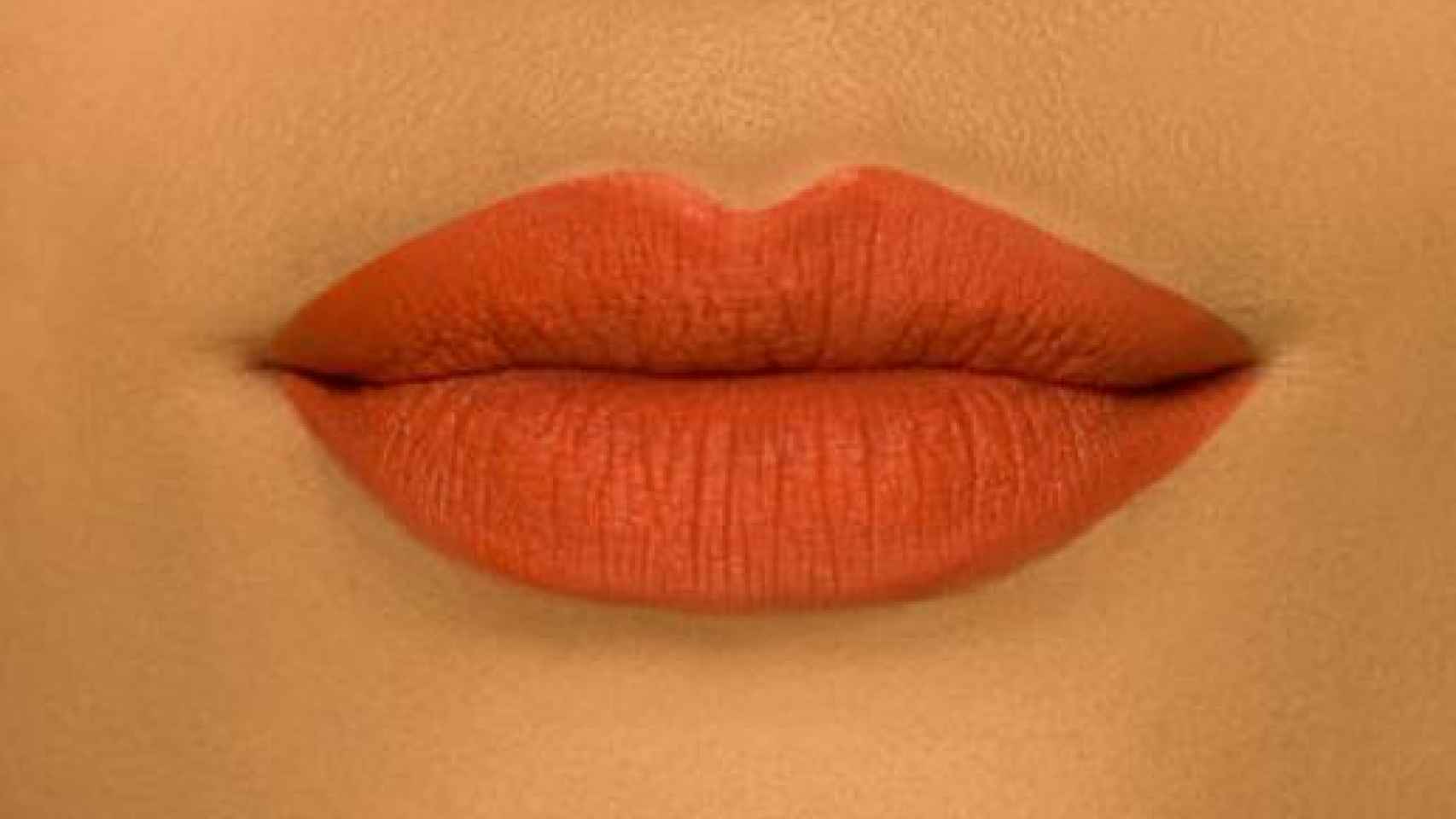 Una modelo de NYX luciendo los labios naranjas.