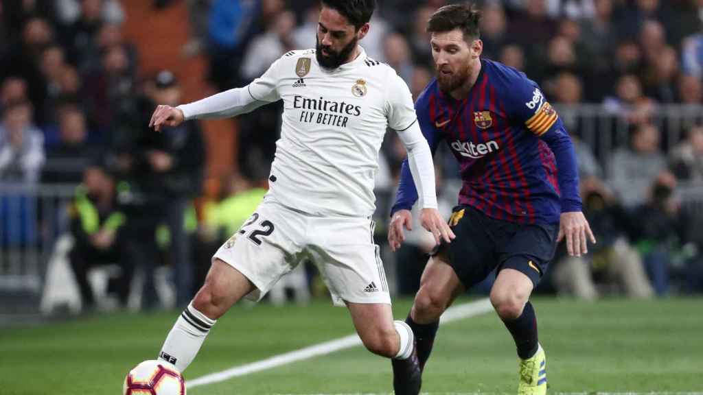 Isco controla un balón presionado por Leo Messi